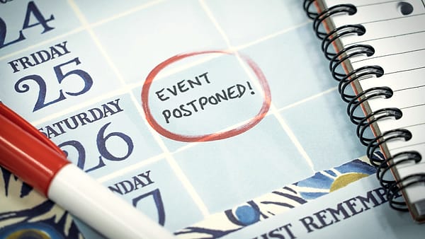 A wall calendar with a date marked and the word postponed written across it