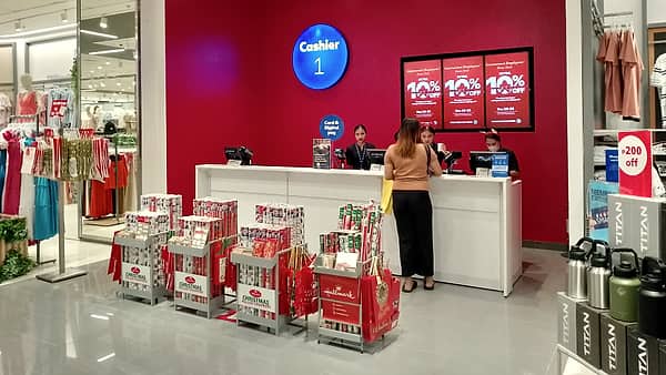 A retail cashier counter with a till and packaging behind it