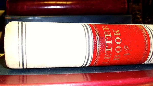 A bound accounting ledger lying open on a table, its ruled columns visible