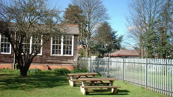 A line of wooden benches along a school corridor lit by daylight