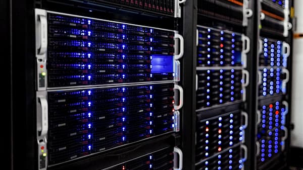 Rows of server racks inside a computer room, cabling running between them