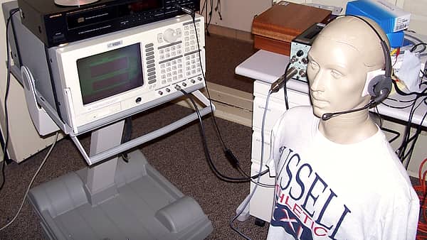 A call center headset resting on a desk beside audio testing equipment