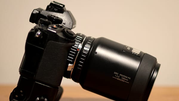 A mirrorless camera body fitted with an adapted lens, photographed from the side