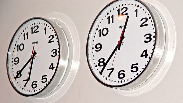 Two wall clocks mounted side by side showing different times in a public building