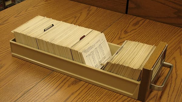 An open card catalog drawer filled with index cards standing upright in rows