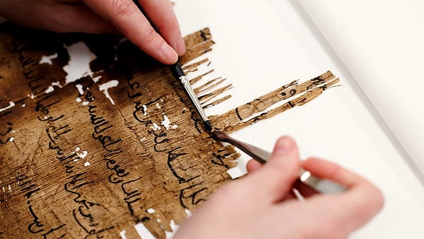 A paper conservator working on fragments of an ancient document at a bench