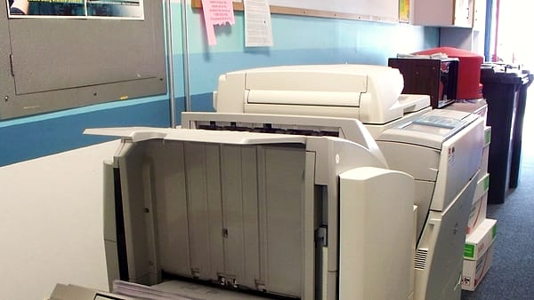 An office photocopier standing in a corridor with its lid closed