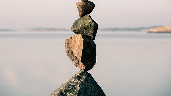 Four smooth stones balanced in a stack on a flat surface outdoors