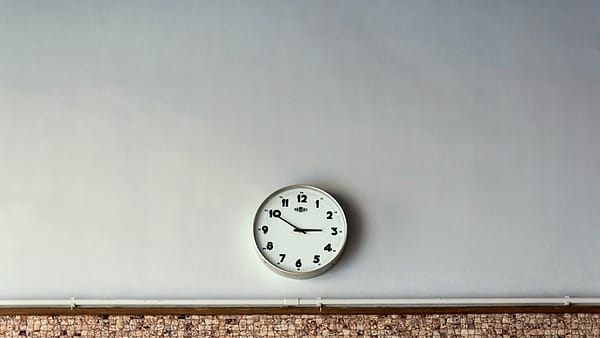 A plain round analog wall clock photographed against a light wall