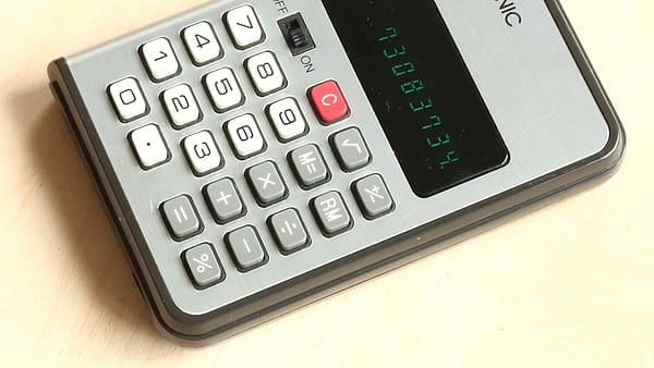 A pocket calculator lying on a flat surface beside printed paperwork