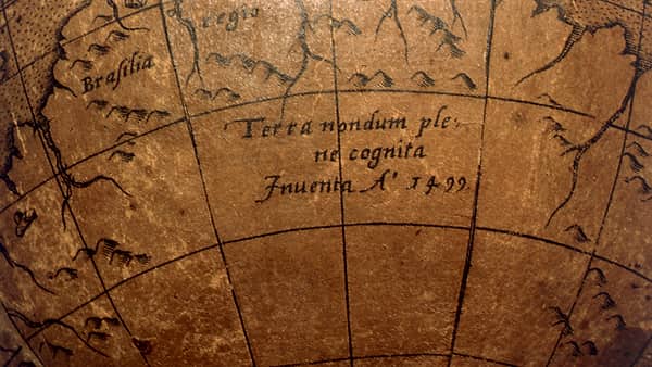 A terrestrial table globe on its wooden stand, photographed against a dark background