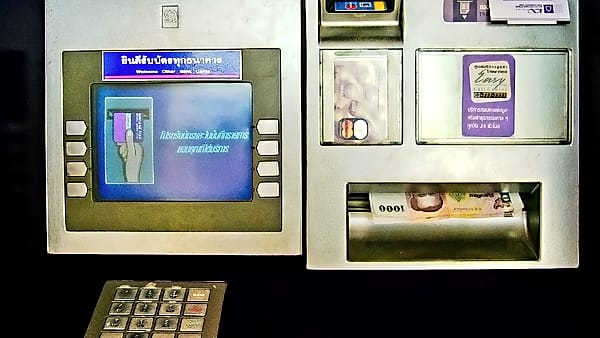 A bank cash machine set into an exterior wall beside its signage