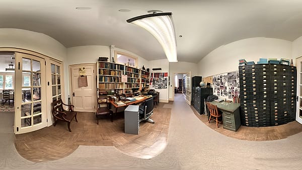 An office with bookshelves along one wall and metal filing cabinets against the other