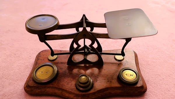 A set of brass balance scales with weights beside them on a table