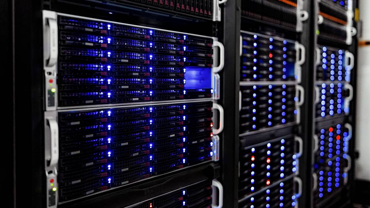 Rows of server racks inside a computer room, cabling running between them