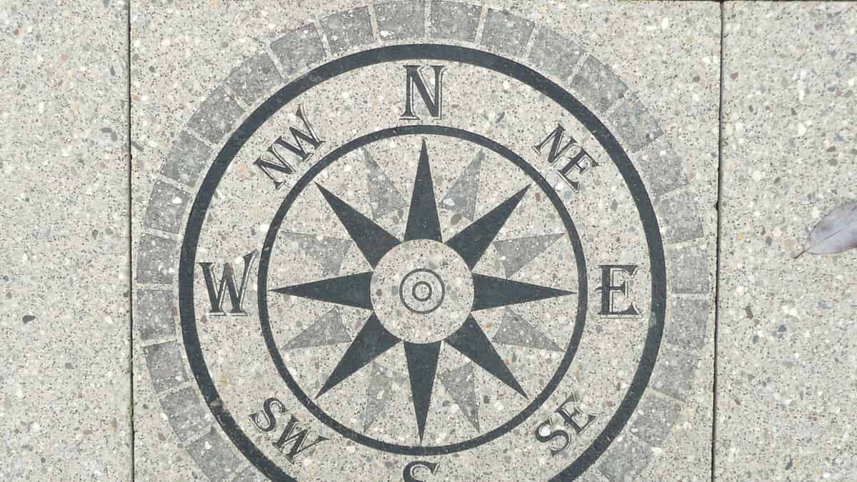 A compass rose set into a stone surface, its points marked around the circle