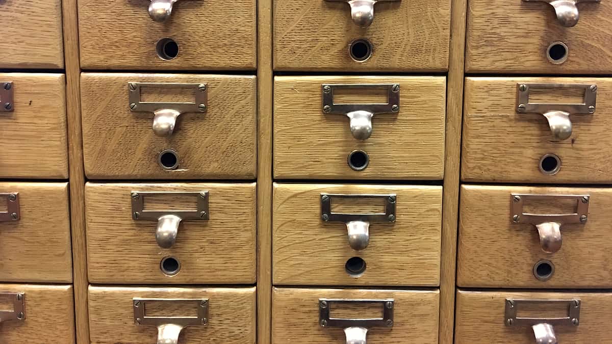 A wooden library card catalog cabinet with its many small drawers closed