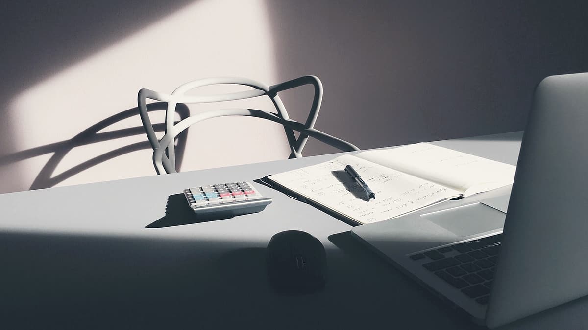 A desk with a laptop, a calculator and papers arranged across it