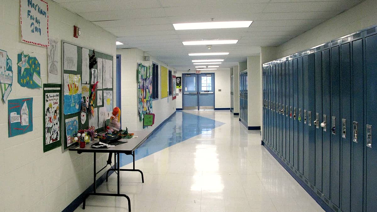An empty school hallway lined with lockers and classroom doors