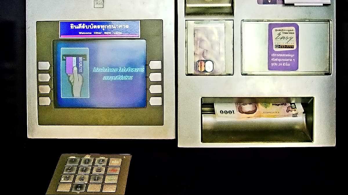 A bank cash machine set into an exterior wall beside its signage